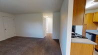 Located at 8101 83rd Ave SW in Lakewood, Washington, this single-floor unit offers a practical and comfortable layout designed for everyday living. The living area features plush wall-to-wall carpeting and flows seamlessly into the dining space, which is finished with light wood-look flooring and accented by a pendant light fixture. Vertical blind-covered windows allow natural light to fill the space while maintaining privacy.

The galley-style kitchen is well-equipped, featuring warm honey-toned wood cabinetry, granite-look countertops, a stainless steel sink, and black appliances including a refrigerator, electric range, and dishwasher. A textured ceiling carries throughout the unit, adding a consistent design element across all rooms.

The bedrooms are generously proportioned, each finished with soft carpeting, vertical blinds on the windows, and baseboard heating units to ensure year-round comfort. Ample closet space is provided within the bedrooms. The bathroom includes a full tub-shower combo with white tile surround, a window for natural ventilation, and a clean, functional layout. Throughout the unit, neutral wall tones and clean finishes create a bright, move-in-ready environment.