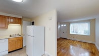 This 2-bedroom, 1-bathroom residence is spread across three floors, offering a practical and comfortable layout. The kitchen is equipped with standard appliances, including a full-size refrigerator, and features tile flooring that transitions seamlessly into the adjoining living areas. Light-toned walls throughout create a bright and airy atmosphere, contributing to the home's clean, neutral aesthetic. The entryway is highlighted by a classic paneled front door with transom windows above, allowing natural light to filter into the space and illuminate the warm hardwood floors that extend through the main living area. Baseboard heating is present, ensuring comfort throughout the seasons. The open sightlines between the kitchen and entryway enhance the sense of flow and connectivity within the home. With three floors of living space, residents benefit from a clear separation between common areas and private quarters. The straightforward, no-frills design makes this home highly functional, while the hardwood flooring and natural light add character and warmth to the overall ambiance.