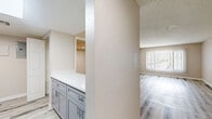 Located at 2601 N 36th Street in Phoenix, Arizona, this one-bedroom, one-bathroom unit offers a thoughtfully updated interior across a single level. Light wood-style laminate flooring runs throughout, complementing the neutral, warm-toned walls and white trim found in every room.

The kitchen is a standout feature, equipped with gray shaker-style cabinetry, brushed nickel hardware, white countertops, a double-basin stainless steel sink, and black appliances including a freestanding range and refrigerator. A skylight adds brightness overhead, while an adjacent open shelving unit provides convenient pantry-style storage.

The living area is bright and open, benefiting from a large window dressed with vertical blinds that allow for natural light and privacy control. The textured ceiling adds dimension to the space. A hallway connects the main living areas to the bedroom and bathroom, offering a practical and private layout.

The bedroom is a comfortable size, featuring the same light laminate flooring, textured walls, and a standard door entry. The bathroom includes a full tub-shower combination, vanity with gray cabinetry matching the kitchen, a wall-mounted mirror, and clean white finishes throughout. The overall aesthetic is cohesive, modern, and move-in ready.