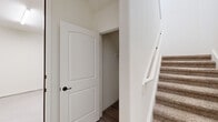 Located in El Paso's Eastlake community, this two-story, two-bedroom, two-bathroom home offers a thoughtfully designed layout spread across two levels. The ground floor houses an attached garage with a concrete floor and automatic door, providing convenient vehicle storage. The main living level features an open-concept kitchen and living area with light wood-look flooring throughout. The kitchen is well-appointed with rich dark cabinetry, granite countertops, stainless steel appliances including a gas range and built-in microwave, a double sink, and pendant lighting over a breakfast bar. Natural light flows generously through multiple windows fitted with blinds. A carpeted staircase with a white railing leads to the upper level, where both bedrooms are located. Each bedroom features carpet flooring, a ceiling fan, and windows offering neighborhood views. The primary bedroom includes a spacious walk-in closet outfitted with built-in shelving and multiple hanging rods. The bathrooms feature dark vanity cabinetry with granite countertops and wood-look tile flooring. A dedicated laundry room with washer and dryer hookups adds everyday convenience. The home maintains a clean, neutral palette throughout, creating a bright and welcoming atmosphere.