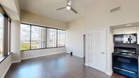 Located at 44 Market Plaza in downtown Montgomery, AL, this one-bedroom, one-bathroom unit offers an efficient and well-designed layout across a single floor. The space makes a strong first impression with its dramatically high ceilings and dark hardwood flooring that run throughout, creating a sense of openness that extends well beyond its compact footprint.

The open living area benefits from large windows that invite abundant natural light, and a ceiling fan adds comfort overhead. The kitchen is neatly integrated into the space, featuring white shaker-style cabinetry, dark countertops, and black appliances including a full-size refrigerator, range, dishwasher, and microwave. A louvered closet door adds a classic architectural touch near the kitchen entry.

The bedroom is a generously proportioned retreat, highlighted by a bold dark accent wall with recessed spotlights that add depth and a stylish focal point. Neutral walls and the continuous hardwood flooring maintain a cohesive aesthetic throughout.

The bathroom is clean and functional, outfitted with a combination tub and shower, a round mirror above the vanity, and a neutral color palette that keeps the space feeling bright and airy. Rich dark hardwood flooring ties the bathroom seamlessly to the rest of the unit's design language.