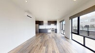 Located at 7 Chestnut St in Norwalk, CT, this modern two-bedroom, one-bathroom residence offers a thoughtfully designed layout with contemporary finishes throughout. Light-toned hardwood-style flooring flows seamlessly across the entire unit, complementing the clean white walls and recessed lighting that give the space a bright, airy feel.

The open-concept kitchen and living area serves as the heart of the home. The kitchen is outfitted with sleek dark cabinetry, stainless steel appliances including a range, dishwasher, and refrigerator, a subway tile backsplash, and ample counter space. Large sliding glass doors flood the living area with natural light and provide direct access to a generously sized outdoor terrace, where open-sky views of the surrounding Norwalk cityscape create an inviting extension of the living space.

The primary bedroom is spacious and features large windows that frame neighborhood views, while a well-appointed walk-in closet with built-in wire shelving offers excellent storage. The full bathroom is finished with large-format floor tiles, white subway tile surrounding the tub and shower, and a dark wood vanity with an integrated sink and mirror.

A connecting hallway leads to the second bedroom, which also benefits from natural light. The overall design aesthetic is clean, modern, and move-in ready.