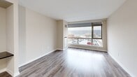 Located on an upper floor at 66 Main Street in Yonkers, NY, this one-bedroom, one-bathroom unit offers a well-designed layout that maximizes functionality and comfort. The living room is a standout space, bathed in natural light through expansive floor-to-ceiling windows that frame sweeping views of the Yonkers skyline and the Hudson River beyond. Durable hardwood-style flooring runs throughout the living areas and bedroom, lending a warm, contemporary feel to the entire unit. The kitchen is thoughtfully appointed with light maple cabinetry, dark granite countertops, a slate tile backsplash, and a full suite of stainless steel appliances including a refrigerator, electric range, and microwave. A breakfast bar provides additional counter space and casual seating. The bedroom is a well-proportioned retreat with neutral walls, hardwood-style flooring, and a dedicated closet for storage. The bathroom features clean, classic white tile surrounding a full soaking tub and shower combination, complemented by a mosaic tile floor, a white vanity, and a large mirror. A washer and dryer are also included within the unit. The overall aesthetic is modern and understated, with a neutral color palette that creates a bright, move-in-ready atmosphere throughout.