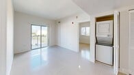 Located at 652 SW 1st St in Miami's vibrant Brickell neighborhood, this 2-bedroom, 2-bathroom unit offers a thoughtfully designed single-floor layout. The kitchen features warm wood cabinetry extending to the ceiling, dark granite countertops with a matching backsplash, stainless steel appliances including an electric range and over-the-range microwave, a double stainless steel sink, and a white dishwasher. Light tile flooring flows from the kitchen into the open living area, which is bright and airy with natural light streaming through a sliding glass door leading to a private balcony. The balcony offers open views of the Miami skyline and surrounding cityscape under the characteristic South Florida sky. A stacked in-unit washer and dryer is conveniently situated in the living area. The bedrooms are generously proportioned, with the primary bedroom benefiting from its own closet space. Two well-sized closets provide ample storage throughout the unit. The bathrooms are cleanly finished with wood vanities, dark granite countertops, large mirrors, and tile surround tub-shower combinations. The unit's clean white walls and tile floors throughout create a bright, neutral canvas well-suited to Miami's sun-filled lifestyle.