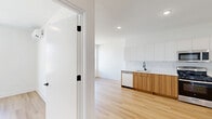 Located on the fifth floor at 17 Martin Luther King Jr Drive in Jersey City, NJ, this one-bedroom, one-bathroom unit offers a clean, modern aesthetic throughout. Light hardwood flooring runs continuously across the open living and kitchen area, enhancing the sense of space and cohesion.

The kitchen is a standout feature, outfitted with two-tone cabinetry — warm wood lower cabinets paired with crisp white upper cabinets — and white quartz countertops. Stainless steel appliances include a gas range, over-the-range microwave, refrigerator, and dishwasher, complemented by a matte black faucet at the undermount sink. Recessed lighting illuminates the space effectively.

The living area is bright and open, featuring a wall-mounted split HVAC unit and a window with open city views. The bedroom is a comfortable, well-proportioned room with a large window framing rooftop and neighborhood views, allowing ample natural light.

The bathroom is finished in a contemporary style with large-format marble-look tile in the shower/tub surround and flooring. A floating wood vanity, white countertop, and matte black fixtures add a sophisticated, cohesive touch throughout.