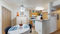 This single-floor residence at 1493 Forest Brooke Way in Delaware, Ohio offers a well-organized layout with distinct living areas designed for everyday comfort. The kitchen is appointed with warm wood cabinetry, white appliances including a range, refrigerator, and dishwasher, as well as a double sink and durable wood-look flooring. A peninsula counter connects the kitchen to a cozy dining area, which features a ceiling fan with light fixture and space for a round dining table. The living room is carpeted and benefits from natural light through a window with valance treatments, creating a welcoming and relaxed atmosphere. The bedroom is a comfortable retreat with plush carpeting, a window with sheer curtains, and ample room for a full-sized bed and furnishings. The full bathroom includes a vanity with sink, wood cabinetry, and a tub-shower combination. A versatile additional room serves as a dedicated home office or den, complete with carpeting and enough space to accommodate a drafting table and filing storage. Textured ceilings are consistent throughout the residence, contributing to a cohesive interior character. The overall layout is practical and efficiently designed, making it a functional and comfortable living space.