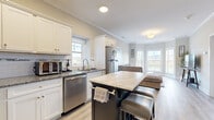 This well-appointed 1-bedroom, 1-bathroom residence at 320 Howe Ave in Shelton, CT offers a thoughtfully designed layout across a single floor. The open-concept kitchen and dining area is a standout feature, showcasing white shaker cabinetry, granite countertops, a classic subway tile backsplash, and a full suite of stainless steel appliances. A contrasting dark-finished island with a marble-style top provides additional prep space and casual seating for two. Light hardwood-style flooring runs throughout, tying the spaces together seamlessly. The living room is bathed in natural light through a striking multi-panel bay window that frames views of the surrounding Shelton landscape, complemented by crown molding that adds a refined architectural touch. The bedroom is a calm, comfortable retreat with ample natural light, crown molding, and two closets offering generous storage. The full bathroom features a white vanity with granite countertops, wood-look tile flooring, and a shower-tub combination. Additional practical spaces include a utility room and extra closet storage. Crown molding is present throughout, elevating the overall aesthetic of this stylish and efficiently designed home.