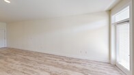 This single-story unit offers a well-organized layout housing three bedrooms, three bathrooms, a kitchen, and a living room within a efficiently arranged floor plan. The open-concept kitchen and living area serves as the heart of the unit, where light wood-look flooring extends throughout. The kitchen is outfitted with crisp white shaker-style cabinetry, black bar pulls, granite countertops, a white subway tile backsplash, and a peninsula with an undermount sink illuminated by pendant lighting overhead. Stainless and black appliances complete the space.

The living area is bright and airy, benefiting from multiple windows with horizontal blinds that allow natural light to filter through, and a door providing direct outdoor access.

The bedrooms feature neutral carpet flooring and windows that bring in natural light. The spacious primary bedroom includes a ceiling fan. The bathrooms maintain a consistent design language with white cabinetry, granite countertops, framed mirrors, and wood-look tile flooring. One bathroom includes ADA-accessible grab bars and a tub with a built-in bench seat. The exterior outlook includes landscaped grounds and views of the broader community.