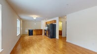 Located at 1175 Fort Hunter Rd in Schenectady, NY, this single-floor, three-bedroom, one-bathroom home offers a practical and comfortable layout throughout. The open-concept kitchen and living area forms the heart of the home, with warm hardwood-style flooring flowing throughout the main living spaces. The kitchen is well-equipped with honey-toned wood cabinetry, dark granite-style countertops, and a full suite of black appliances including a refrigerator, range, built-in microwave, and dishwasher. A breakfast bar peninsula connects the kitchen to the expansive living area, which is bathed in natural light through large windows offering views of the surrounding wooded landscape. The three bedrooms are carpeted for comfort and feature neutral walls, providing a clean canvas for personalization. The primary bedroom is generously sized and includes a double sliding-door closet. The full bathroom is finished with tile flooring, a combined tub and shower with grab bar, a wood-cabinet vanity, and an oversized mirror. Clean lines, recessed lighting, and a neutral color palette throughout contribute to the home's bright and functional ambiance.