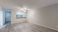 Located at 4225 Mangum Rd in Houston, TX, this single-story unit offers a clean, updated interior with a cohesive neutral color palette throughout. Light gray luxury vinyl plank flooring runs consistently across all living areas, providing both durability and a modern aesthetic.

The living area is open and airy, featuring a ceiling fan with light fixture and a pass-through window that connects directly to the kitchen, enhancing the sense of openness. The galley-style kitchen is efficiently laid out with white cabinetry lining both sides, white appliances including a refrigerator and range, a built-in dishwasher, and a single-basin sink — all finished with light countertops that complement the overall bright design.

The bedrooms are well-proportioned, each equipped with ceiling fans and large windows fitted with blinds that allow ample natural light. One bedroom features a closet with built-in shelving and a dedicated in-unit laundry area with a stacked washer and dryer setup, adding notable convenience.

The bathroom includes a full tub-shower combination with white subway tile surround, a grab bar for added safety, chrome fixtures, and a standard toilet — all presented in a clean, functional design. Textured ceilings and white trim throughout complete the interior's polished, move-in-ready appearance.