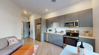 Located at 41 Seacoast Terrace in Kittery, Maine, this one-bedroom, one-bathroom residence offers a thoughtfully designed open-concept layout with modern finishes throughout. Light wood-tone flooring runs continuously through the living and kitchen areas, creating a warm, cohesive aesthetic.

The kitchen is well-appointed with sleek gray flat-front cabinetry, white countertops, and a full suite of stainless steel appliances, including a refrigerator, dishwasher, electric range, and microwave. A single-basin sink with a matte black faucet anchors the space, and recessed lighting provides clean, even illumination throughout. A dedicated in-unit laundry closet is conveniently accessible just off the kitchen area.

The living area flows naturally from the kitchen, offering a comfortable space for everyday use. The bedroom is a generously proportioned private retreat, featuring clean white walls, continued wood-tone flooring, and a paneled gray interior door with black hardware that adds a contemporary touch.

The bathroom is finished with large-format light gray tile flooring, a gray vanity, matte black hardware and towel bar, a full soaking tub with shower, and open wire shelving for added storage.

This residence combines functional design with modern, low-maintenance finishes, making it a practical and attractive home in coastal southern Maine.