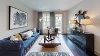 This well-appointed single-floor residence showcases a thoughtfully designed layout that balances modern aesthetics with everyday functionality. Dark hardwood flooring flows seamlessly throughout the entire unit, creating a cohesive and sophisticated foundation for each space.

The kitchen is a standout feature, outfitted with floor-to-ceiling wood-toned cabinetry, stainless steel appliances including a refrigerator, range, microwave, and dishwasher, and a crisp white countertop island with seating. Track lighting overhead highlights the clean lines and contemporary finishes of this highly functional cooking space.

The living area is bright and welcoming, anchored by large windows and a glass door that opens onto a private balcony, inviting natural light and outdoor views into the room. The generous layout comfortably accommodates a full seating arrangement, lending the space an open and airy feel.

The bedroom is a calm retreat, featuring a sizable window that fills the room with natural light and offers views of the surrounding exterior. Neutral wall tones and dark hardwood floors contribute to the room's relaxed, modern ambiance.

The bathroom connects directly to the bedroom and includes a soaking tub with tiled surround, a floating vanity with ample drawer storage, white countertops, and well-lit mirrors — all finished with the same dark hardwood flooring for a consistent, upscale look throughout.