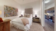Located at 2017 Second Ave S in Birmingham, Alabama, this single-floor residence offers a thoughtfully designed layout with refined finishes and a cohesive aesthetic throughout. The open kitchen serves as a functional centerpiece, featuring rich wood-grain cabinetry extending floor to ceiling, granite countertops, a classic white subway tile backsplash, and a full suite of stainless steel appliances including a range, microwave, dishwasher, and refrigerator. Dark hardwood-style flooring grounds the space and carries through into the main living areas.

The living room is elegantly appointed, showcasing elevated ceilings, a tufted cream sofa, a large upholstered ottoman, and a woven area rug that adds warmth and texture. A pair of large-scale abstract paintings in gold and neutral tones anchors the room, while a wall-mounted television and floor lamp complete the space. Sliding glass doors invite natural light and provide access to an outdoor area.

The bedroom exudes a calm, sophisticated atmosphere with plush carpeting, a generously sized tufted headboard, and carefully selected artwork and decorative accents, including a distinctive sunburst mirror. The bathroom features clean, modern finishes with white subway tile in the walk-in shower and wood-look flooring, maintaining the residence's consistent attention to detail.
