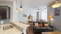 This thoughtfully designed 1-bedroom, 1-bathroom residence offers a comfortable and functional single-floor layout. The open-concept living and dining area is anchored by rich hardwood flooring, a ceiling fan, and large windows fitted with blinds that invite generous natural light. A leather sofa, rustic wood coffee table, and wall art create a warm, inviting atmosphere, while a dedicated dining nook provides additional space for entertaining.

The kitchen is a standout feature, boasting dark espresso cabinetry that extends to the ceiling for ample storage, light granite countertops, a subway tile backsplash, and a full suite of stainless steel appliances including a side-by-side refrigerator with ice and water dispenser, electric range, and built-in microwave. A peninsula with an undermount sink and pendant lighting doubles as a breakfast bar with seating.

The bedroom is a serene retreat, featuring multiple windows for natural light, hardwood floors, a walk-in closet, and a tufted upholstered headboard. The full bathroom offers a classic aesthetic with hexagonal tile flooring, a dark vanity with white countertop, and a tub-shower combination with white subway tile surround.