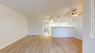 Located at 2345 Newport Blvd in Costa Mesa, CA, this 2-bedroom, 1-bathroom unit offers a well-organized single-floor layout designed for comfortable everyday living. Light wood-style flooring runs throughout the entire space, creating a cohesive and bright aesthetic. The open-concept living and kitchen area anchors the home, where a peninsula counter with a granite-style surface separates the kitchen from the living room, making it ideal for both entertaining and daily use. A ceiling fan overhead adds a functional touch to the living area. The kitchen features white cabinetry, white appliances including a gas range, dishwasher, and refrigerator, as well as a stainless steel sink and under-cabinet range hood. The primary bedroom is a well-proportioned room that receives natural light through a large window with outdoor views of surrounding greenery, and includes a sliding glass door leading to an exterior space. Both bedrooms feature light flooring and ample wall space. One bedroom includes a sliding-door closet with built-in shelving and a rod. The shared bathroom includes a full tub and shower combination with chrome fixtures and a grab bar. A hallway connects the main living areas to the bedrooms, with a dedicated closet providing additional storage.
