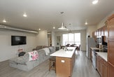 This single-floor residence is designed with an open-concept layout that seamlessly connects the kitchen, dining, and living areas, creating a cohesive and functional living environment. The kitchen is well-appointed with rich medium-toned wood cabinetry, light countertops, stainless steel appliances, and a spacious island with pendant lighting overhead—providing both additional workspace and casual seating. Exposed ductwork adds an industrial accent to the space. The living area features recessed lighting and durable wood-look flooring that extends throughout the main living spaces.

The dining area is positioned adjacent to large sliding glass doors that open to a private balcony, allowing generous natural light and outdoor views to enhance the space. Both bedrooms offer ceiling fans, carpeted floors, and notable closet storage. Each of the two bathrooms features warm wood cabinetry, a single-sink vanity with a light countertop, wood-look tile flooring, and a tub-shower combination. A dedicated in-unit laundry area accommodates a full-sized washer and dryer. Overall, the space presents a practical and comfortable layout with modern finishes throughout.