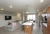 This single-floor residence is designed with an open-concept layout that seamlessly connects the kitchen, dining, and living areas, creating a cohesive and functional living environment. The kitchen is well-appointed with rich medium-toned wood cabinetry, light countertops, stainless steel appliances, and a spacious island with pendant lighting overhead—providing both additional workspace and casual seating. Exposed ductwork adds an industrial accent to the space. The living area features recessed lighting and durable wood-look flooring that extends throughout the main living spaces.

The dining area is positioned adjacent to large sliding glass doors that open to a private balcony, allowing generous natural light and outdoor views to enhance the space. Both bedrooms offer ceiling fans, carpeted floors, and notable closet storage. Each of the two bathrooms features warm wood cabinetry, a single-sink vanity with a light countertop, wood-look tile flooring, and a tub-shower combination. A dedicated in-unit laundry area accommodates a full-sized washer and dryer. Overall, the space presents a practical and comfortable layout with modern finishes throughout.