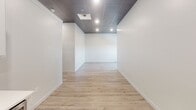 Located at 230 S Phillips Ave in the heart of downtown Sioux Falls, South Dakota, this single-floor commercial space combines modern finishes with a functional, adaptable layout. Throughout the unit, dark drop-panel tile ceilings contrast cleanly with bright white walls, while recessed lighting provides consistent illumination across each area.

The kitchen is well-appointed with white shaker-style cabinetry, a textured tile backsplash, stainless steel appliances including a refrigerator, range, microwave, and dishwasher, and light wood-look luxury vinyl plank flooring. An integrated sink with a modern faucet completes the setup, making it suitable for a breakroom or studio kitchen.

Open rooms throughout the space offer flexible use, with some featuring light LVP flooring and others finished with patterned commercial carpet, accommodating a range of configurations from office to retail or studio use.

The bathroom is fully updated, showcasing large-format porcelain tile flooring, a walk-in glass-enclosed shower with marble-style wall tile, a built-in niche, pebble stone flooring, and a white vanity. Clean white walls and modern fixtures contribute to a polished, contemporary feel throughout the entire unit.