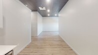 Located at 230 S Phillips Ave in the heart of downtown Sioux Falls, South Dakota, this single-floor commercial space combines modern finishes with a functional, adaptable layout. Throughout the unit, dark drop-panel tile ceilings contrast cleanly with bright white walls, while recessed lighting provides consistent illumination across each area.

The kitchen is well-appointed with white shaker-style cabinetry, a textured tile backsplash, stainless steel appliances including a refrigerator, range, microwave, and dishwasher, and light wood-look luxury vinyl plank flooring. An integrated sink with a modern faucet completes the setup, making it suitable for a breakroom or studio kitchen.

Open rooms throughout the space offer flexible use, with some featuring light LVP flooring and others finished with patterned commercial carpet, accommodating a range of configurations from office to retail or studio use.

The bathroom is fully updated, showcasing large-format porcelain tile flooring, a walk-in glass-enclosed shower with marble-style wall tile, a built-in niche, pebble stone flooring, and a white vanity. Clean white walls and modern fixtures contribute to a polished, contemporary feel throughout the entire unit.