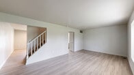 This two-story home at 749 Kelford Pl in Trotwood, Ohio offers a practical and well-organized layout across two floors. The main level features a bright, open living room with light-toned luxury vinyl plank flooring and neutral white walls that create a clean, airy atmosphere. A staircase with white railings connects the main level to the upper floor. The kitchen is equipped with gray cabinetry, granite-look countertops, a double-basin sink, and white appliances including a refrigerator and dishwasher, all set over matching LVP flooring. A hallway on the main level provides access to additional rooms and exits. Upstairs, four bedrooms offer comfortable living space, each finished with plush carpeting and neutral-toned walls. The spacious primary bedroom features dual windows that invite natural light and offer views of surrounding greenery. The two full bathrooms include tub/shower combinations with tile surrounds in warm beige tones. Throughout the home, consistent use of light colors and clean finishes contributes to a bright, move-in ready feel. Two hallways and dual staircases ensure smooth circulation between floors, making this a functional and versatile home.