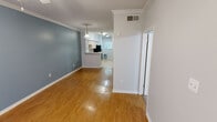 Located at 2904 Swisher St. in Austin, TX, this single-story, 2-bedroom, 2-bathroom home offers a comfortable and functional layout. The living and dining areas feature warm wood-look flooring, crown molding, and a cool blue accent wall, creating an inviting atmosphere. A pendant light adds a touch of character to the dining space, which flows seamlessly into the kitchen via a breakfast bar pass-through. The kitchen is well-equipped with light wood cabinetry, ample counter space, tile flooring, black appliances including a refrigerator, dishwasher, and electric range, plus a window that brings in natural light with garden views. A dedicated laundry area houses a full-size side-by-side washer and dryer. The bedrooms are carpeted for comfort; the primary bedroom includes a ceiling fan, a window with outdoor views, and access to a walk-in closet with built-in shelving. The primary bathroom features a vanity with a single sink and a large mirror. The second bedroom also offers carpet flooring and a ceiling fan. Crown molding throughout the living areas and consistent neutral tones give the home a cohesive, polished feel well-suited for Austin living.