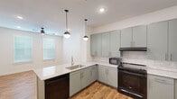 Located at 1000 E Yager Ln in Austin, TX, this one-bedroom, one-bathroom unit offers a thoughtfully designed single-floor layout with modern finishes throughout. Warm wood-look flooring flows consistently across all rooms, creating a cohesive and inviting atmosphere.

The kitchen serves as a central highlight, featuring sage green cabinetry with gold hardware, granite speckle countertops, a subway tile backsplash, and black stainless steel appliances including a range, refrigerator, and dishwasher. A peninsula with pendant globe lighting provides additional counter space and opens naturally into the living area, which is illuminated by recessed lighting and a ceiling fan.

The bedroom is a comfortable, well-proportioned space with two windows fitted with blinds that allow ample natural light. A ceiling fan adds practical comfort, and the room connects to a dedicated closet for storage.

The bathroom continues the design language of the kitchen, with matching sage green vanity cabinetry, granite countertops, gold hardware accents, and a large mirror with wall-mounted sconce lighting. The clean white walls throughout the unit enhance brightness and create a fresh, contemporary feel.

This well-appointed unit combines functional design with modern aesthetics, making it a polished and practical home in northeast Austin.