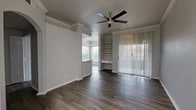 Located at 6233 Love Dr in Irving, TX, this one-bedroom, one-bathroom residence offers a thoughtfully designed single-floor layout. The living area makes a strong impression with rich dark hardwood-style flooring, crown molding, and a ceiling fan. A built-in shelving unit with a built-in desk nook adds functional character, while a large sliding glass door with vertical blinds fills the space with natural light. The living area flows seamlessly into the dining area, which features an elegant chandelier and generous windows.

The kitchen is well-appointed with white shaker cabinetry, a central island with an undermount sink, stainless steel appliances including a refrigerator, dishwasher, microwave, and range, plus light wood-tone flooring that complements the clean, modern aesthetic.

The bedroom is carpeted for comfort and is equipped with a ceiling fan and a window with natural light. It connects directly to a spacious walk-in closet outfitted with wire shelving and hanging rods. The bathroom features a white vanity with ample drawer storage, a soaking tub and shower combination, and light wood-tone flooring. A hallway off the bathroom provides convenient access to an in-unit washer and dryer area.