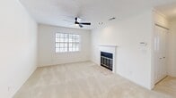 Located at 9000 W Wilderness Way in Shreveport, Louisiana, this well-appointed single-floor unit offers a practical and comfortable layout across a compact but efficient footprint. The open-concept kitchen and living area form the heart of the home, where a striking marble-look countertop with a double undermount sink serves as both a functional workspace and a visual centerpiece. The kitchen is equipped with white cabinetry, black appliances including a refrigerator, electric range, and over-the-range microwave, plus ample storage with a pantry closet. The living room features plush neutral carpeting, a ceiling fan with a built-in light, a classic fireplace with a white mantel, and a window with blinds that invites natural light. A chandelier is visible from the living area, adding a decorative touch near the kitchen pass-through. The bedroom is generously sized, featuring soft carpeting, a ceiling fan, a large double-door closet for ample storage, and windows that bring in natural light. The textured ceilings throughout add subtle architectural character. The space maintains a clean, neutral palette that creates a bright and inviting atmosphere throughout.