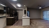 Located at 2811 La Frontera Blvd in Round Rock, Texas, this single-floor residence offers a well-designed layout with a cohesive modern aesthetic throughout. The open-concept kitchen is a standout feature, showcasing dark espresso cabinetry, stainless steel appliances including a refrigerator, microwave, and range, complemented by light quartz countertops and a kitchen island with a built-in sink. Wood-look luxury vinyl flooring runs through the kitchen and hallway areas, creating a clean contrast with the plush carpeting found in the living and bedroom spaces. A large wall mirror in the kitchen area enhances the sense of openness and reflects natural light effectively. The bedrooms are generously proportioned, each equipped with ceiling fans and neutral-toned carpet, offering a comfortable and functional retreat. One bedroom benefits from a window with blinds that allows natural light to filter in. The bathrooms maintain the design continuity of the space, featuring dark vanity cabinetry, white quartz countertops, wood-look vinyl flooring, and clean white fixtures. One bathroom includes a full tub and shower combination, while another presents a more elongated layout with additional storage. The overall ambiance is contemporary and understated, with a neutral color palette and consistent finishes that lend a polished, move-in-ready feel.