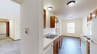Located at 1180 Matt Urban Dr in Holland, Michigan, this two-story home offers a functional and well-organized layout across two floors. The main level houses the primary living spaces, including a combined dining room and galley-style kitchen equipped with warm wood cabinetry, white appliances including a range and refrigerator, a double-basin sink, and wood-look flooring that extends through the area. A dedicated dining space adjoins the kitchen and benefits from natural light through a window. The living room is notably spacious, featuring soaring ceilings and access to an outdoor deck, with a ceiling fan overhead adding to the airy feel. A convenient entrance, hallway, and a full bathroom complete the main floor. Upstairs, a loft overlooks the main living area, complemented by a second full bathroom with a tub-shower combination. Both bedrooms are carpeted and bright, each with windows that invite natural light. The primary bedroom offers a generous footprint with a closet. Textured ceilings, wood-trimmed doors and baseboards, and a neutral color palette are consistent throughout, creating a clean and cohesive interior. Two closets provide ample storage across the home.