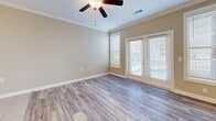 Located at 191 Waters Edge Cir in Waynesville, NC, this well-appointed 2-bedroom, 2-bathroom single-floor home offers a comfortable and functional layout with quality finishes throughout. The open living room is bright and inviting, featuring light gray hardwood-style flooring, warm neutral-toned walls, crown molding, a ceiling fan, and French doors that flood the space with natural light and provide access to an outdoor area. The kitchen is thoughtfully designed with rich dark cabinetry, granite-look countertops, tile flooring, a stainless steel refrigerator, range, and microwave, as well as a dedicated sink area — offering both style and practicality. The spacious primary bedroom includes crown molding, large windows, and direct access to the outdoors, while the second bedroom also benefits from generous natural light and a closet. A walk-in closet with wire shelving systems provides ample storage in the primary suite. Both bathrooms mirror the kitchen's aesthetic with dark vanity cabinetry, granite countertops, tile flooring, and brushed nickel fixtures. The consistent use of neutral tones and quality materials throughout creates a cohesive, clean, and modern ambiance suited for comfortable everyday living.