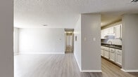 Located at 9901 Brockington Rd in Sherwood, Arkansas, this single-floor, 2-bedroom, 2-bathroom home offers a practical and well-organized layout. The living area features light-toned luxury vinyl plank flooring, neutral gray walls, a textured ceiling, and a large window that brings in natural light and street views, creating a bright and open atmosphere. A pass-through connects the living space to the galley-style kitchen, which is lined with white cabinetry, dark countertops, and black appliances including a range, refrigerator, and dishwasher, all set over matching vinyl plank flooring. A central hallway links the main living spaces to the private sleeping quarters. Both bedrooms are carpeted and feature ceiling fans with integrated lighting. The spacious primary bedroom includes a dedicated closet and direct access to one of the two bathrooms. The second bedroom offers a sliding-door closet for ample storage. Both bathrooms are consistent in design, each featuring white cabinetry, dark countertops, a single-basin sink, a full tub-shower combination with built-in shelving, and vinyl plank flooring. The overall palette throughout is clean and neutral, creating a cohesive and move-in ready environment.