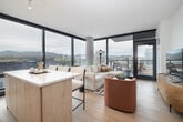 This contemporary 2-bedroom, 2-bathroom residence in Boise, Idaho offers a thoughtfully designed single-floor layout with high-end finishes and sweeping views of the downtown skyline and surrounding mountains. Light hardwood flooring flows throughout, complemented by crisp white walls and recessed lighting that create a clean, modern aesthetic.

The open-plan living, dining, and kitchen area is anchored by dramatic floor-to-ceiling windows on two sides, flooding the space with natural light and framing breathtaking panoramic views. A sliding glass door leads to a private patio, perfect for outdoor relaxation. The kitchen features white cabinetry and generous counter space.

The spacious primary bedroom enjoys its own floor-to-ceiling window with city views, a dedicated closet, and direct access to a well-appointed en-suite bathroom. The primary bath offers a double-sink vanity with a light wood cabinet, backlit mirrors, and a glass-enclosed shower. The second bedroom also benefits from large windows with city views. The second bathroom includes a tiled soaking tub and shower combo with a matching wood vanity.

A welcoming hallway with light wood flooring and curated wall art connects all rooms, reinforcing the space's cohesive, modern design sensibility.