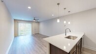 Located at 4781 Transit Rd in Depew, NY, this thoughtfully designed one-bedroom, one-bathroom residence offers a comfortable and modern living experience across a single floor. Light-toned hardwood-style flooring flows seamlessly throughout, unifying the open-concept layout.

The combined dining and living area is bright and airy, featuring recessed lighting, a ceiling fan, and large sliding glass doors that open to a private balcony, filling the space with natural light and offering outdoor access. The kitchen is a standout feature, equipped with rich dark espresso cabinetry, white quartz countertops, a peninsula with an undermount sink, stainless steel appliances including a range, microwave, and refrigerator, and elegant pendant lighting overhead.

The generously sized primary bedroom provides a comfortable retreat, complemented by two closets, including a spacious walk-in closet outfitted with wire shelving for ample storage. The bathroom continues the refined aesthetic with a dark wood vanity, white quartz countertop, and a well-lit mirror. Additional conveniences include a dedicated laundry area, utility room, and an entry hallway. The unit's clean, neutral palette and modern finishes create a cohesive and welcoming ambiance throughout.