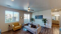 This single-floor unit showcases a contemporary design with a cohesive, modern aesthetic throughout. The open-concept living area is finished with rich wood-look flooring and features a ceiling fan, a large sliding glass door leading to a private balcony, and an adjacent window that together fill the space with natural light and outdoor views of the surrounding community.

The kitchen is a standout feature, centered around a granite-topped island with bar seating and an integrated sink. Light wood cabinetry extends to the ceiling, complemented by stainless steel appliances including a refrigerator, range, and microwave. Pendant lighting above the island adds warmth, while recessed ceiling lights provide thorough illumination throughout the cooking space.

The bedroom is carpeted for comfort and benefits from elevated horizontal windows that allow natural light while maintaining privacy. A ceiling fan is present, and a walk-in closet offers generous storage. The room connects conveniently to the rest of the unit via a paneled interior door.

The bathroom is finished with wood-look tile flooring, a granite-topped vanity, and a full tub-shower combination. Neutral tones throughout create a clean, cohesive feel that carries across all areas of the unit.