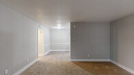This one-bedroom, one-bathroom residence in Charlotte, NC offers a thoughtfully arranged single-floor layout designed to maximize functionality. The living room is carpeted in warm tan tones and painted in soft gray, creating a neutral and inviting atmosphere. It connects seamlessly to a hallway that leads throughout the unit. The galley-style kitchen is well-appointed with white cabinetry, white countertops, a stainless steel sink, and white appliances including a refrigerator and range. Light wood-look flooring runs through the kitchen and dining area, adding a clean, contemporary feel. The combined kitchen and dining space provides a practical area for everyday living. The bedroom is generously sized, featuring plush carpeting, soft gray walls, and two windows that allow natural light to filter in. Two closet doors in the bedroom offer ample storage. A second closet elsewhere in the unit provides additional storage convenience. The bathroom includes a full tub-shower combination with chrome fixtures and clean white finishes. Throughout the space, white baseboards and neutral gray walls maintain a cohesive, modern aesthetic. The layout is efficient and well-connected, making it a practical and comfortable residence in Charlotte's 28208 area.