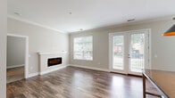Located at 1221 E Broadway in Louisville, KY, this well-appointed 2-bedroom, 2-bathroom apartment offers a thoughtfully designed single-floor layout. The open living room makes a strong first impression with rich hardwood-style flooring, crown molding, and a sleek built-in electric fireplace framed by a crisp white mantel. Natural light pours in through multiple windows and a set of French doors that open to a private outdoor space, creating a bright and airy atmosphere throughout.

The kitchen is outfitted with white shaker cabinetry, dark granite countertops, a light blue subway tile backsplash, and a full suite of stainless steel appliances, including a range, microwave, and refrigerator. Hardwood-style flooring continues here, tying the space together seamlessly.

Both bedrooms feature plush carpeting and ceiling fans. A standout detail in the primary bedroom is a rustic sliding barn door that opens to an en-suite bathroom with marble-style tile surround. The second bathroom includes a tub/shower combination with similarly elegant tile finishes. Three closets, including a spacious walk-in with wire shelving, provide ample storage. An in-unit laundry area adds everyday convenience to this stylish Louisville residence.