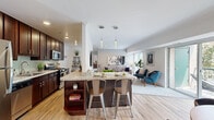 Located at 8130 Prescott Dr in Vienna, VA, this well-appointed 2-bedroom, 1-bathroom residence offers a thoughtfully designed single-floor layout that maximizes comfort and functionality. The open-concept living, dining, and kitchen area serves as the heart of the home, anchored by warm hardwood flooring that flows seamlessly throughout the main living spaces. The kitchen features rich dark wood cabinetry, granite countertops, stainless steel appliances including a gas range and microwave, and a central island with pendant lighting and bar seating — ideal for casual dining and entertaining. The dining area enjoys direct access to an outdoor balcony through a sliding glass door, inviting abundant natural light and greenery views. The living room extends the open layout, offering generous space with large windows that bathe the room in natural light. The spacious primary bedroom features plush carpeting, a ceiling fan, and ample room for full bedroom furnishings. The second bedroom is equally comfortable with soft carpeting, natural light, and access to the hallway. A full bathroom with tub/shower combo and tile flooring completes the layout. A connecting hallway provides easy access to all rooms, rounding out this clean, functional, and inviting Vienna residence.