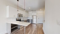 Located at 535 Main St in Nashville's vibrant 37206 zip code, this modern one-bedroom, one-bathroom unit offers a thoughtfully designed open-concept layout with clean, contemporary finishes. Wood-look flooring runs throughout the main living areas, tying the kitchen, dining, and living spaces together seamlessly.

The kitchen is a standout feature, equipped with a full suite of stainless steel appliances including a refrigerator, range, microwave, and dishwasher. White upper cabinetry contrasts stylishly with wood-toned lower cabinets, while a white subway tile backsplash and light countertops complete the modern aesthetic. Pendant lights with red accent cords add a distinctive design touch. A built-in breakfast bar provides additional seating and workspace.

The living room is bright and airy, benefiting from large windows that invite generous natural light and a ceiling fan overhead. The bedroom features plush carpeting, its own ceiling fan, and a sizable window with outdoor views, creating a comfortable and restful retreat.

The bathroom offers a refined feel with granite countertops, wood-toned cabinetry, an undermount sink, and a glass-enclosed walk-in shower with tiled walls. A dedicated laundry area adds everyday convenience. The unit also includes a private entryway, contributing to an overall sense of privacy and ease.
