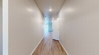 This single-story home offers a well-organized, functional layout across four bedrooms and two full bathrooms. Light-toned wood-look flooring runs consistently throughout the interior, contributing to a cohesive, clean aesthetic. Recessed lighting illuminates the hallways and main living areas, while windows fitted with horizontal blinds allow natural light into the bedrooms.

The kitchen and living area share an open-plan layout, anchored by a central island with a stainless steel sink and granite-style countertops. White shaker-style cabinetry lines the walls alongside stainless steel appliances, including a French-door refrigerator and range. A built-in pantry provides additional storage.

The spacious primary bedroom includes a generous walk-in closet equipped with double hanging rods and shelving. The bathrooms feature white vanities with large mirrors, wood-look flooring, and a tub-shower combination. A dedicated laundry room includes washer and dryer hookups and a storage shelf. The oversized two-car garage offers ample parking and storage space, with windows providing natural ventilation. Two connecting hallways guide circulation throughout the home.