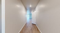 This single-story home offers a well-organized, functional layout across four bedrooms and two full bathrooms. Light-toned wood-look flooring runs consistently throughout the interior, contributing to a cohesive, clean aesthetic. Recessed lighting illuminates the hallways and main living areas, while windows fitted with horizontal blinds allow natural light into the bedrooms.

The kitchen and living area share an open-plan layout, anchored by a central island with a stainless steel sink and granite-style countertops. White shaker-style cabinetry lines the walls alongside stainless steel appliances, including a French-door refrigerator and range. A built-in pantry provides additional storage.

The spacious primary bedroom includes a generous walk-in closet equipped with double hanging rods and shelving. The bathrooms feature white vanities with large mirrors, wood-look flooring, and a tub-shower combination. A dedicated laundry room includes washer and dryer hookups and a storage shelf. The oversized two-car garage offers ample parking and storage space, with windows providing natural ventilation. Two connecting hallways guide circulation throughout the home.