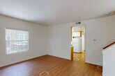 This two-floor residence offers a well-organized layout with a consistent, clean aesthetic defined by crisp white walls and warm hardwood-style flooring throughout the main living areas. The open living room provides a bright, welcoming atmosphere, with natural light streaming through windows and a clear sightline into the kitchen beyond.

The kitchen is thoughtfully designed with white cabinetry accented by warm wood trim, light countertops, and a full suite of appliances including a gas range, built-in microwave, dishwasher, and refrigerator. A double-basin sink is positioned beneath a window, allowing for natural light while cooking or cleaning.

A dedicated laundry area houses a full-size washer and dryer set beneath wall-mounted cabinetry, offering convenient in-unit laundry with added storage.

The bedrooms feature a mix of hardwood-style and carpeted flooring, each with closet space. One carpeted bedroom benefits from multiple windows, filling the room with ample natural light and views of surrounding greenery.

The bathrooms are well-appointed; one features a dual-sink vanity with generous counter space and mirrored panels, while a second full bath includes a tub-shower combination, single vanity, and a bright window. The overall ambiance of the space is clean, functional, and move-in ready.