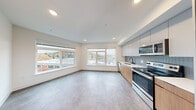 Located in Seattle's vibrant 98144 corridor, this contemporary 2-bedroom, 2-bathroom residence offers a well-designed open-concept layout filled with natural light. The combined living and kitchen area is anchored by large windows that frame sweeping views of the surrounding cityscape and tree-covered hillsides, creating a bright and airy atmosphere throughout the day.

The kitchen is thoughtfully appointed with two-tone cabinetry — pairing crisp white upper cabinets with warm wood-toned lower units — set against a herringbone tile backsplash. Stainless steel appliances, including a range, microwave, dishwasher, and refrigerator, complete the functional yet stylish space.

Both bedrooms are finished in a clean, neutral palette with durable flooring and sliding-door closets equipped with built-in shelving. The primary bedroom benefits from a dedicated window with urban views. Each bedroom is served by its own bathroom, both featuring warm wood vanities, white quartz countertops, under-mount sinks, and matte black fixtures. One bathroom includes a full soaking tub and shower combination, while both are finished with large mirrors and recessed lighting.

A connecting hallway and three closets provide ample storage throughout. The consistent use of neutral tones, modern hardware, and quality finishes gives this residence a cohesive, contemporary character.