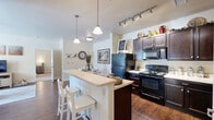 Located at 804 Stone Park Ln in Woodland Park, Colorado, this single-floor, 2-bedroom, 2-bathroom home offers a thoughtfully designed layout that makes efficient use of its space. The kitchen is a standout feature, showcasing rich dark-espresso cabinetry with ample storage, light countertops, black appliances including a range and built-in microwave, and hardwood-style flooring. A peninsula with bar seating and dual pendant lighting creates a natural gathering spot and connects the kitchen to the rest of the living area. The living room is bright and welcoming, with large windows that invite natural light and a ceiling fan overhead. Hardwood-style floors carry through the main living areas, adding warmth and cohesion. The bedrooms are carpeted and comfortably sized, with the primary bedroom featuring multiple windows and a generous walk-in closet equipped with wire shelving. The two bathrooms are finished with dark vanity cabinetry, light countertops, and hardwood-style floors, maintaining a consistent design aesthetic throughout. A hallway connects the rooms efficiently, contributing to a smooth and functional floor plan. The overall ambiance is clean, neutral, and modern, well-suited to the natural surroundings of Woodland Park.