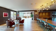 Located at 1550 Vine St in the heart of Hollywood, this single-floor space blends industrial-chic design with warm, inviting interiors. Wide-plank hardwood flooring runs throughout, unifying distinct zones that each offer their own character and function.

The main lounge area features soaring double-height ceilings, dramatic exposed brick columns, and floor-to-ceiling windows that flood the space with natural light while framing views of the surrounding cityscape and outdoor terrace. Leather seating, layered area rugs, and pendant lighting contribute to a sophisticated yet comfortable atmosphere.

A more intimate lounge section with charcoal-painted walls, bold red artwork, and clusters of tufted leather armchairs connects seamlessly to a glass-enclosed sunroom furnished with contemporary sofas, opening directly to an outdoor area through French doors.

A dedicated workspace or bar area features a wraparound dark countertop with built-in cabinetry, pendant lighting, and a wall-mounted display screen, providing a functional and polished environment for collaborative use.

The space also includes a kitchen area equipped with a stainless steel French-door refrigerator. Throughout, the design balances raw industrial elements—exposed ductwork, brick, and wood—with refined furnishings, creating a versatile and visually compelling environment.