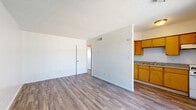 Located at 3827 E Third St in Tucson, Arizona, this single-floor unit offers a straightforward and functional layout designed for comfortable everyday living. The open-concept living area flows seamlessly into the kitchen, which is equipped with warm honey-toned wood cabinetry, ample counter space, an integrated sink, and a freestanding range — providing everything needed for meal preparation. The living space features durable wood-look flooring that extends throughout the unit, clean white walls, and a textured ceiling. A central dividing wall helps define the living and kitchen zones while maintaining an open feel. Natural light enters through a large window and a glass-paneled entry door, brightening the main living area. The bedroom is generously sized with painted cinder block walls, wood-look flooring, and a window fitted with vertical blinds that allow for adjustable natural light. The bathroom includes a vanity with a countertop sink, storage cabinetry below, a wall-mounted mirror with overhead lighting, and a full shower and tub combination. Central HVAC with ceiling vents ensures year-round climate comfort throughout the unit. This space presents a clean, move-in ready environment in a convenient Tucson location.