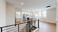 Located at 370 Carmelina Ave in Columbus, OH, this modern two-story home offers 3 bedrooms and 3 bathrooms thoughtfully distributed across two well-proportioned floors. The upper level serves as the main living area, highlighted by an open-concept kitchen featuring white shaker cabinetry, a subway tile backsplash, stainless steel appliances, and a central island with a white quartz countertop illuminated by elegant gold pendant lights. Large windows flood the space with natural light, while a sleek black metal railing staircase connects both levels. The lower floor houses the bedrooms, each finished with warm hardwood-style flooring and bright windows. The primary bedroom includes a dedicated walk-in closet with built-in wire shelving for organized storage. The three bathrooms maintain a consistent modern aesthetic, showcasing white cabinetry with matte black hardware, quartz countertops, and glass-enclosed shower stalls with black framing. A convenient half bath is also located on the main level. Throughout the home, light gray walls, recessed lighting, and cohesive hardwood-style flooring create a clean, contemporary ambiance that is both functional and visually appealing.