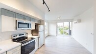 Located at 713 E 29th Ave in Spokane, WA, this well-designed one-bedroom, one-bathroom unit offers a clean, modern aesthetic throughout. Light wood-tone flooring runs seamlessly across the entire space, complementing the crisp white walls and creating a bright, cohesive atmosphere.

The open-concept living and kitchen area is a standout feature. The kitchen is outfitted with two-tone shaker-style cabinetry in soft sage and white, stainless steel appliances including a refrigerator, electric range, over-the-range microwave, and dishwasher, along with white quartz countertops and a stainless steel sink. Track lighting overhead adds a modern touch. A large sliding glass door floods the living area with natural light and opens to a private balcony overlooking lush greenery.

A dedicated closet near the entrance houses a stacked in-unit washer and dryer, adding everyday convenience. The bedroom is a calm, neutral retreat featuring a window with outdoor views and a wall-mounted mini-split unit for climate control.

The bathroom is clean and functional, featuring a full soaking tub with shower, a vanity with storage, and wood-tone flooring that ties the space together. The entrance provides a welcoming transition into the home, with a thoughtful layout that maximizes every inch of the well-proportioned floor plan.
