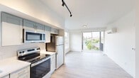 Located at 713 E 29th Ave in Spokane, WA, this well-designed one-bedroom, one-bathroom unit offers a clean, modern aesthetic throughout. Light wood-tone flooring runs seamlessly across the entire space, complementing the crisp white walls and creating a bright, cohesive atmosphere.

The open-concept living and kitchen area is a standout feature. The kitchen is outfitted with two-tone shaker-style cabinetry in soft sage and white, stainless steel appliances including a refrigerator, electric range, over-the-range microwave, and dishwasher, along with white quartz countertops and a stainless steel sink. Track lighting overhead adds a modern touch. A large sliding glass door floods the living area with natural light and opens to a private balcony overlooking lush greenery.

A dedicated closet near the entrance houses a stacked in-unit washer and dryer, adding everyday convenience. The bedroom is a calm, neutral retreat featuring a window with outdoor views and a wall-mounted mini-split unit for climate control.

The bathroom is clean and functional, featuring a full soaking tub with shower, a vanity with storage, and wood-tone flooring that ties the space together. The entrance provides a welcoming transition into the home, with a thoughtful layout that maximizes every inch of the well-proportioned floor plan.