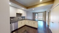 Located at 20 Front St in Hartford, CT, this one-bedroom, one-bathroom residence offers a well-designed layout across a single floor. The open-concept kitchen and living area serves as the heart of the home, featuring rich dark hardwood floors that extend throughout the main living space. The kitchen is outfitted with white cabinetry, dark granite countertops, a mosaic tile backsplash, and a full suite of stainless steel appliances including a range, microwave, dishwasher, and refrigerator. A peninsula provides additional counter space and helps define the transition between kitchen and living area. Large floor-to-ceiling windows flood the living room with natural light and offer views of the surrounding streetscape. The spacious bedroom is finished with plush carpeting and its own set of large windows, continuing the theme of natural light throughout. Three closets provide ample storage, and an in-unit laundry area adds everyday convenience. The bathroom features large-format tile flooring, a dark wood vanity with an undermount sink, and a well-lit mirror. Neutral warm tones and recessed lighting create a clean, modern ambiance throughout the residence.